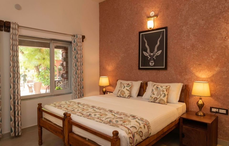 Mandore Premium bedroom Mandore Premium room with wooden bed, bedside lamps and Rajasthani artwork at The Mandore, Jodhpur